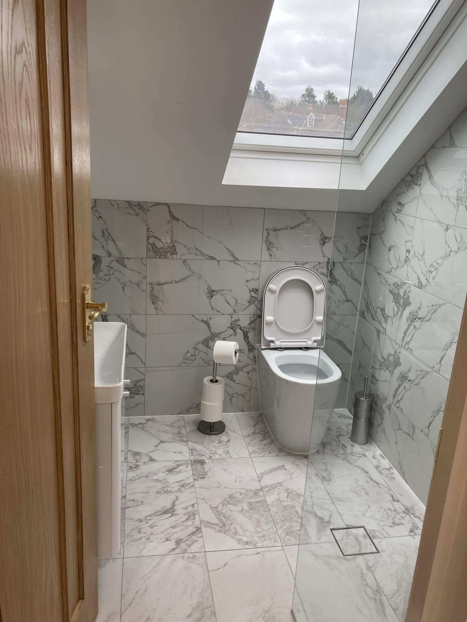 Calacatta marble en-suite bathroom with skylight and brass detailing in a Sevenoaks family home